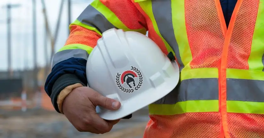 Construction worker holding hard hat symbolizing commercial construction challenges in NJ and throughout the United States.